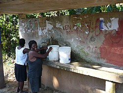 Haitian women transporting water in open buckets.