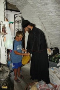 A monk gives a young refugee some provisions.